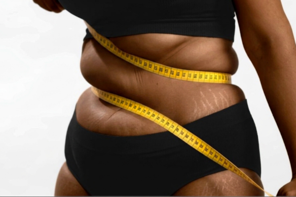 black woman measuring weight with tape